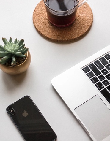 Birds eye view of a laptop, a cactus, tea and an iphone